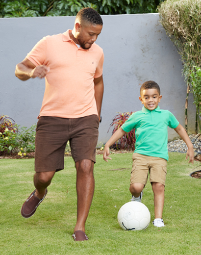 father and son playing football in their back yard